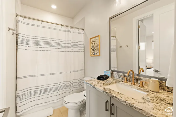 Vanity with a light-toned stone countertop, undermount sink, and brass-finish fixtures