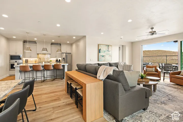 Open-concept living space with wood-finish flooring, recessed lighting, and a ceiling fan