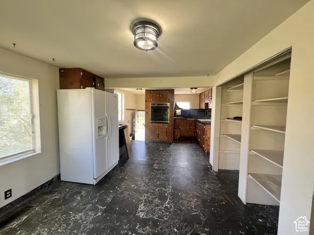 Kitchen area featuring wood cabinetry, built-in oven, and a pantry with shelving