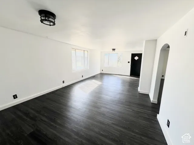 Expansive living area with wood-finish flooring, white walls, multiple windows, and recessed lighting