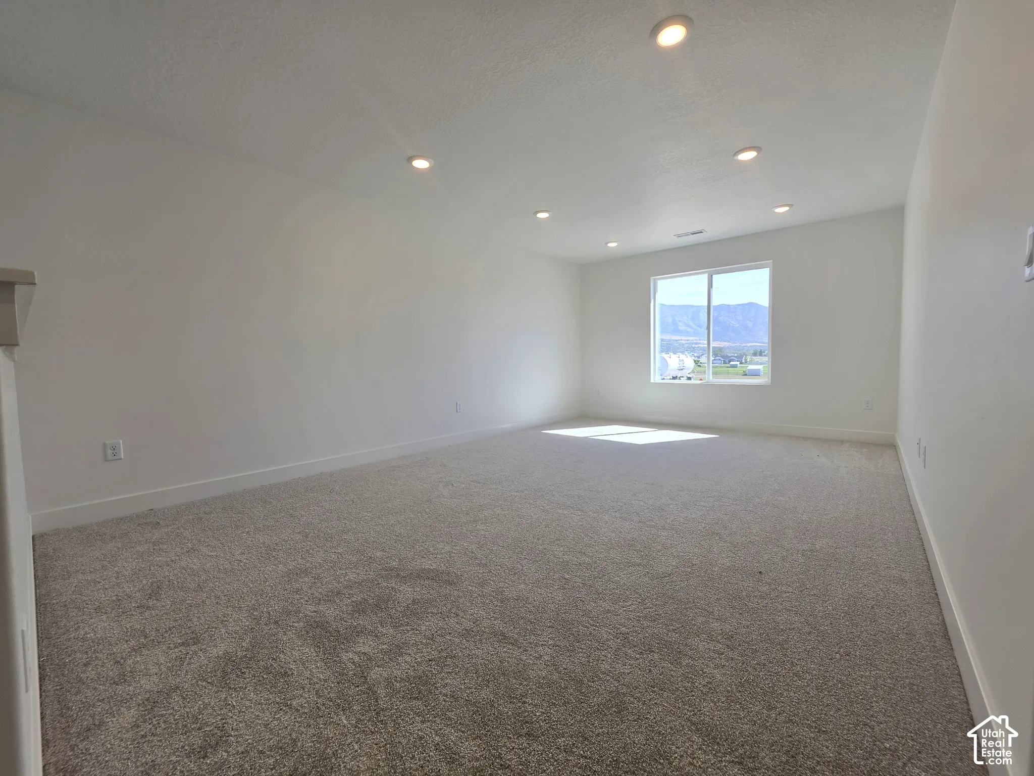 Spacious room featuring carpet flooring, recessed lighting, and a large window with mountain scenery