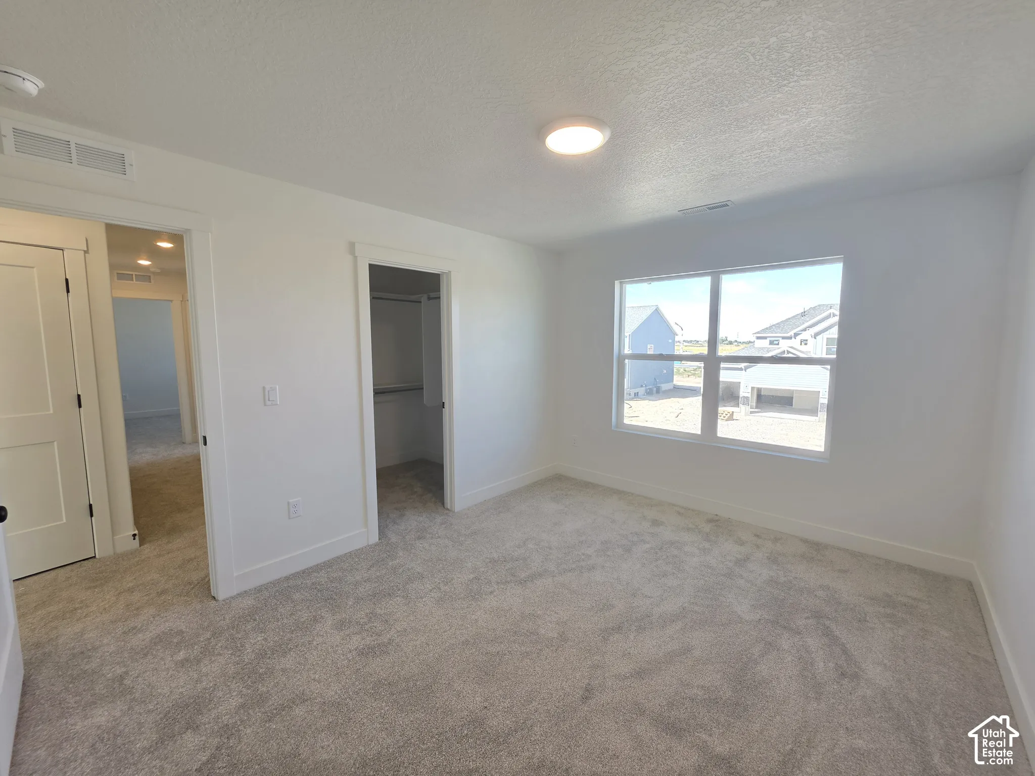 Carpeted room with a large window, built-in closet, and overhead lighting