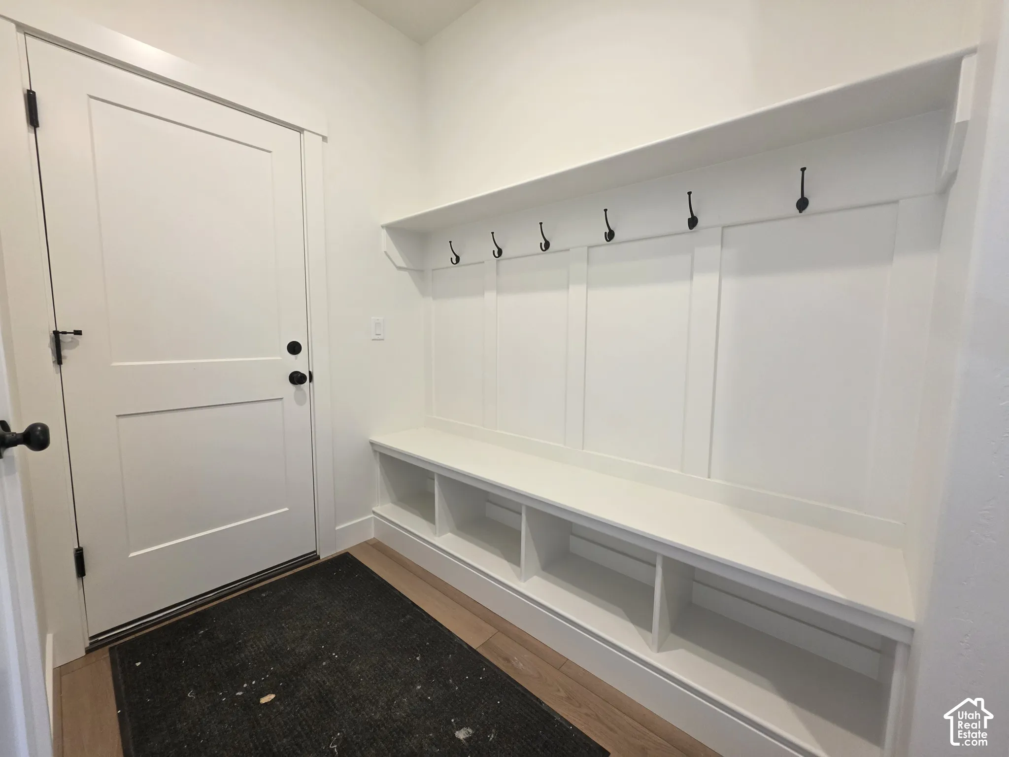 Built-in mudroom bench with storage cubbies, wall hooks, and upper shelf