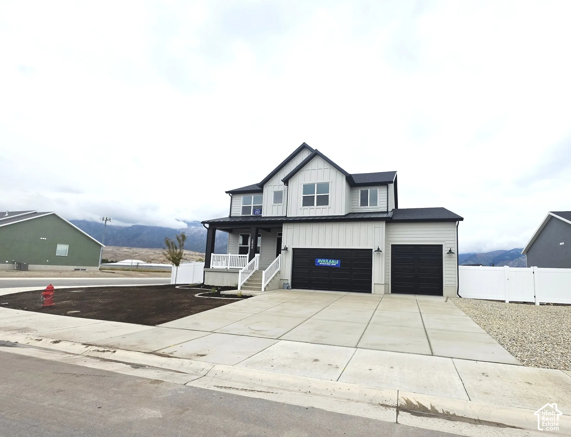 Modern two-story residence with a covered front porch, white railings, and a two-car garage
