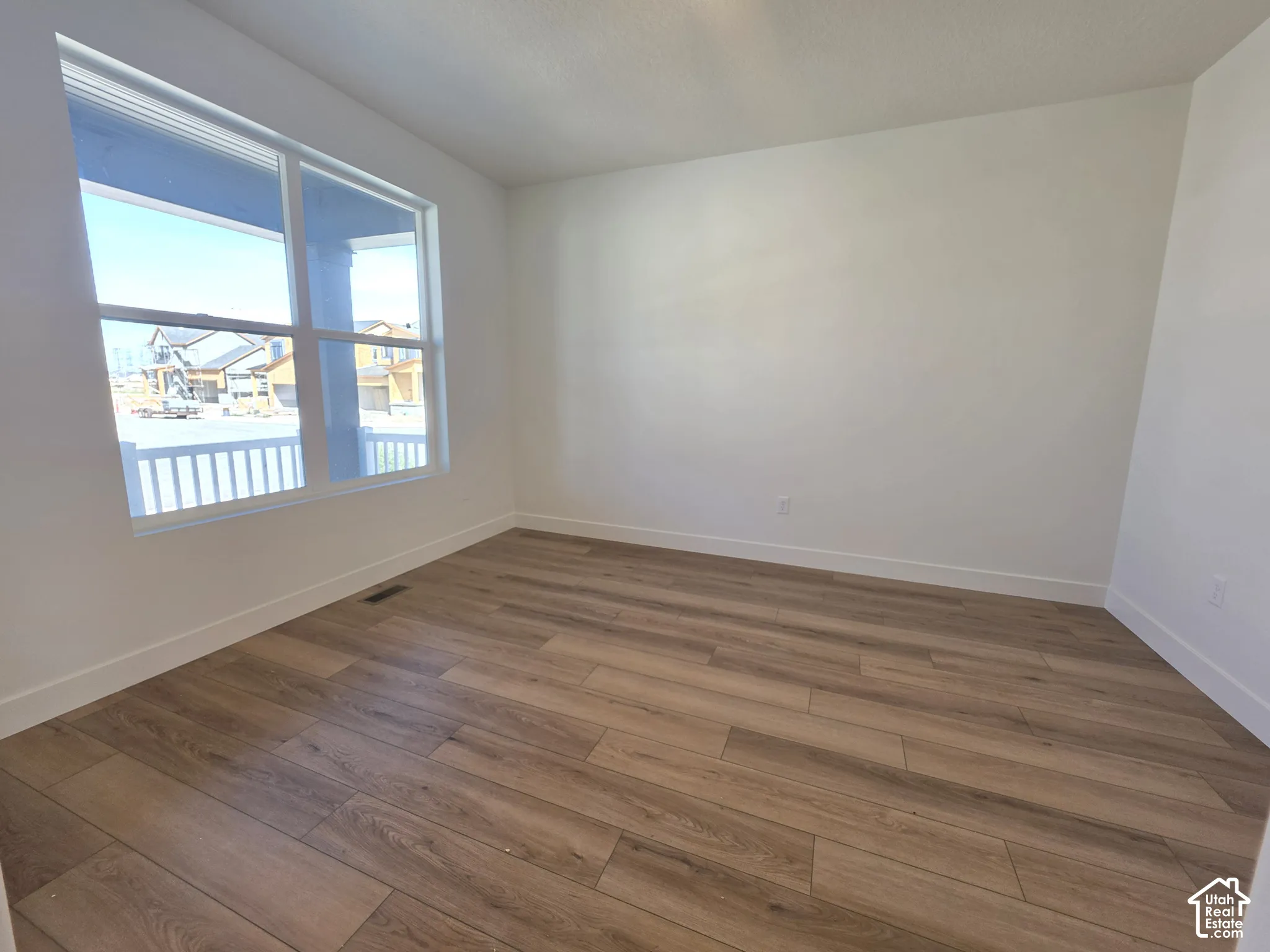 Light wood-finish flooring, white walls, and a large window with white trim