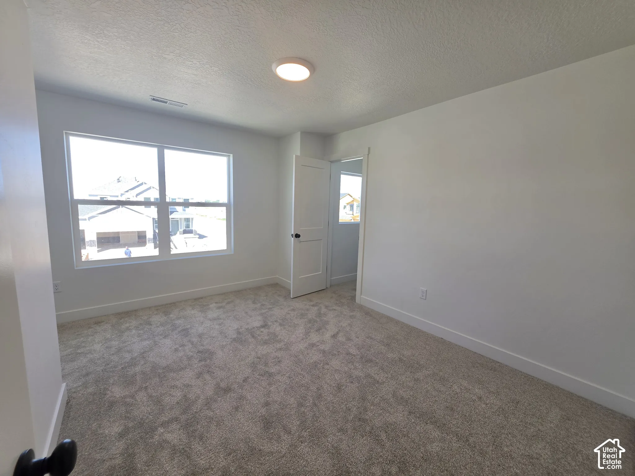 Carpeted flooring, white walls, and a large window
