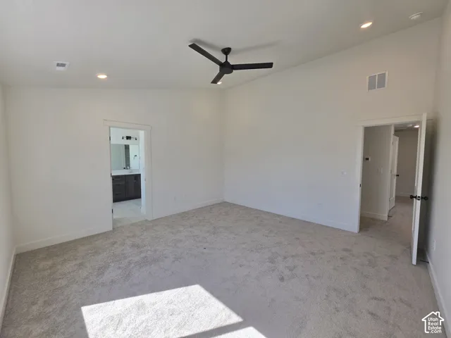 Spacious room with vaulted ceilings, recessed lighting, a ceiling fan, and plush carpeting