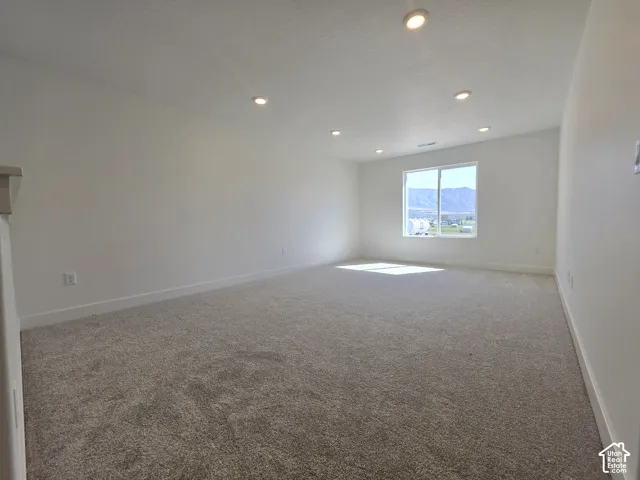 Spacious room featuring carpet flooring, recessed lighting, and a large window with mountain scenery