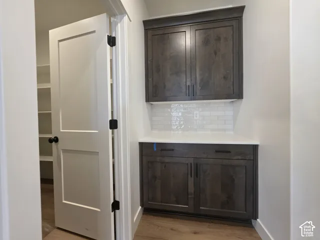 Built-in cabinetry with dark wood finish, white countertop, and subway tile backsplash