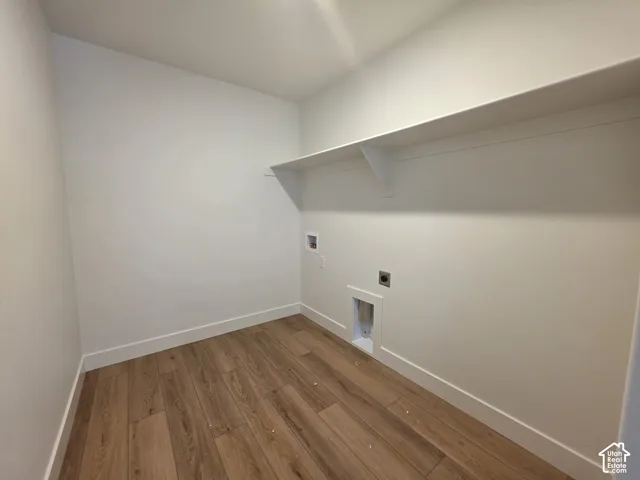 Wood-finish flooring with white baseboards, white walls, and a built-in white shelf