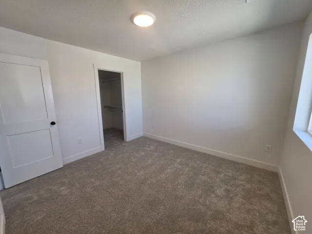 Neutral-toned carpeting, white walls, and a contemporary ceiling light fixture