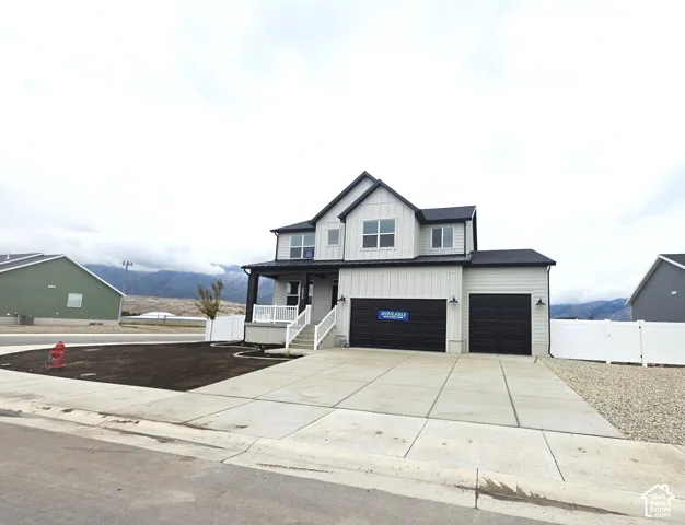 Modern two-story residence with a covered front porch, white railings, and a two-car garage