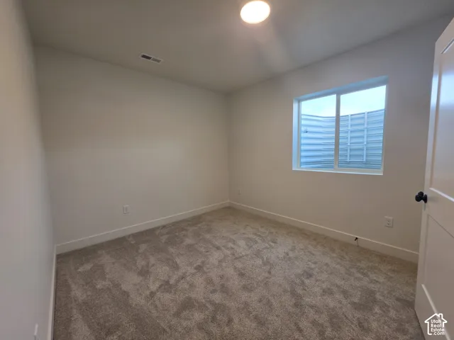 Neutral-toned carpet flooring with white walls and a single window