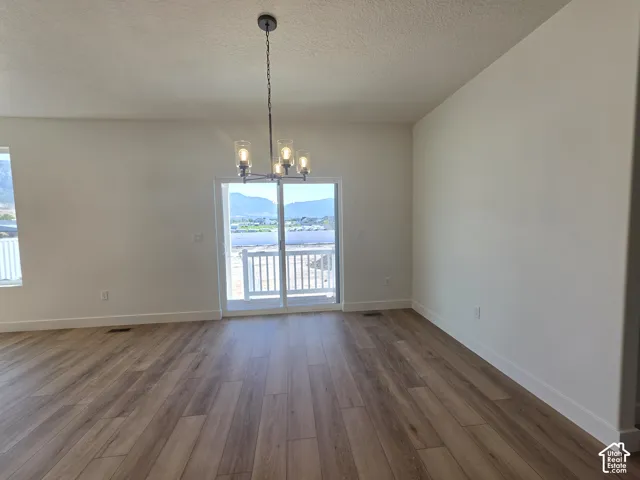 Spacious interior with wood-finish flooring, a modern chandelier, and white walls