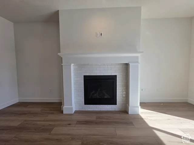 Fireplace with white subway tile surround, classic white mantel, and wood-finish flooring