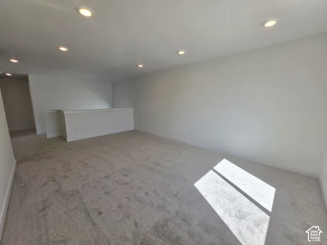 Recessed lighting illuminates the carpeted floor and perimeter wall