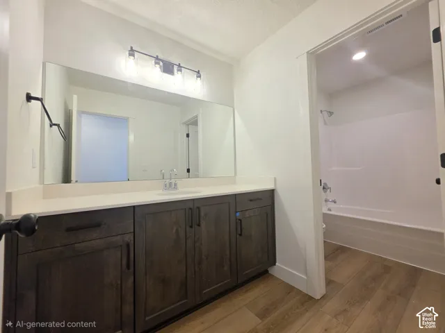Spacious vanity with wood-finish cabinetry, light-toned countertop, and an expansive wall-mounted mirror