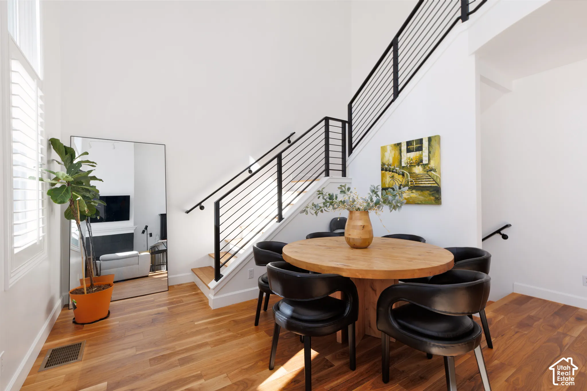 Hardwood flooring, white walls, and a modern staircase with black horizontal railings