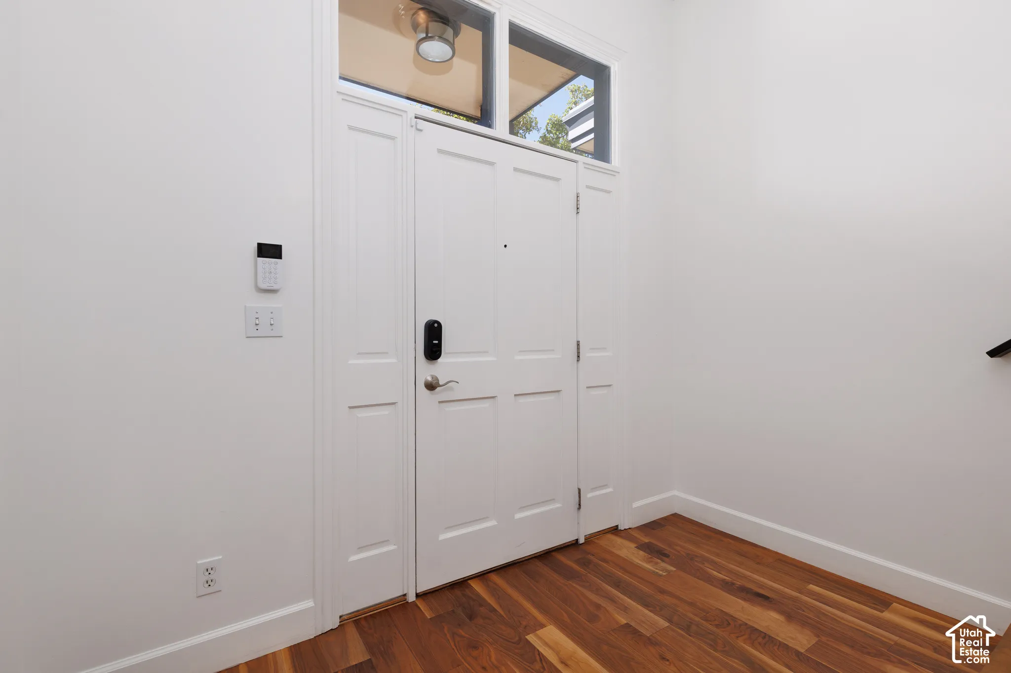 Entryway featuring a white paneled door, transom window, and wood-finish flooring