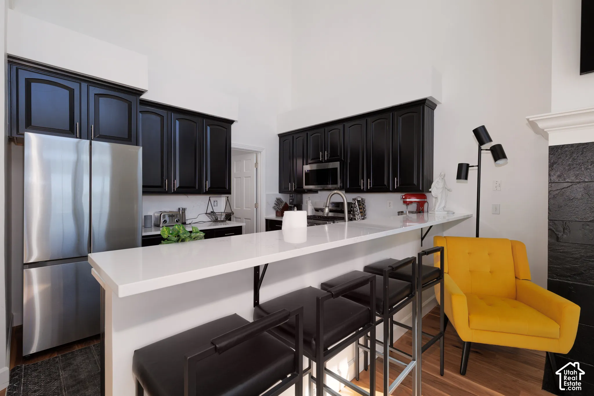 Kitchen featuring dark cabinetry, stainless steel appliances, white countertops, and a breakfast bar