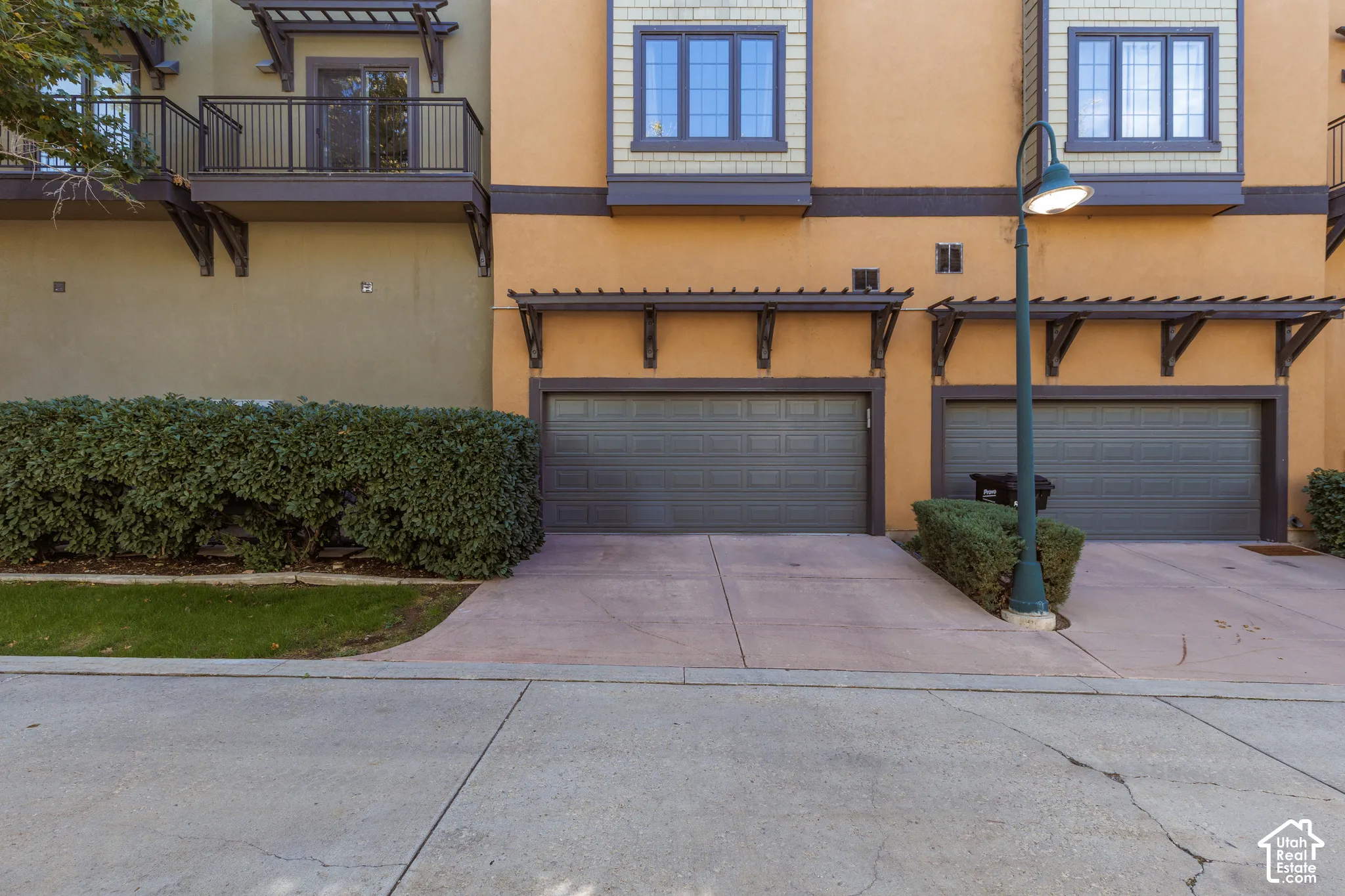 Stucco exterior with multiple windows, two garage doors, and a wrought iron balcony