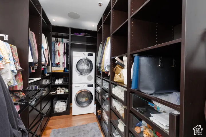 Custom closet system with integrated washer and dryer, recessed lighting, wood-finish flooring, and ample built-in shelving