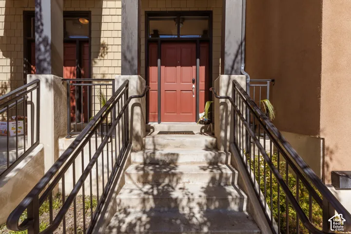 Concrete steps with metal handrails leading to a red entry door