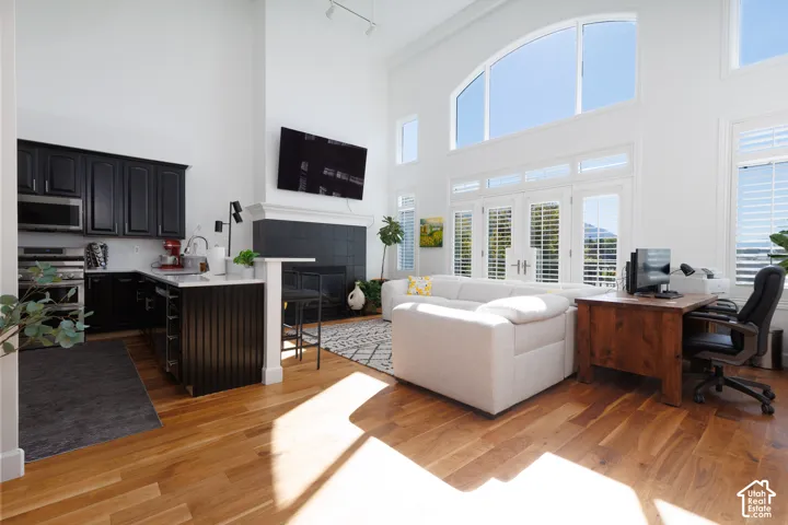 Vaulted ceilings, wood-finish flooring, white walls, and a fireplace with a black tile surround