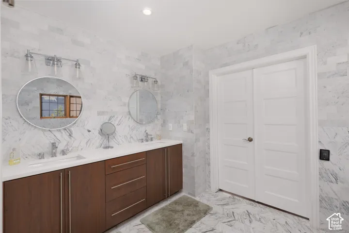Double vanity with wood-finish cabinetry, circular mirrors, and a white countertop