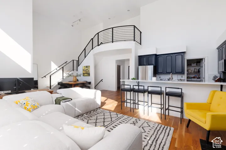 Vaulted ceilings, wood-finish flooring, staircase with metal railings, kitchen island, and dark cabinetry