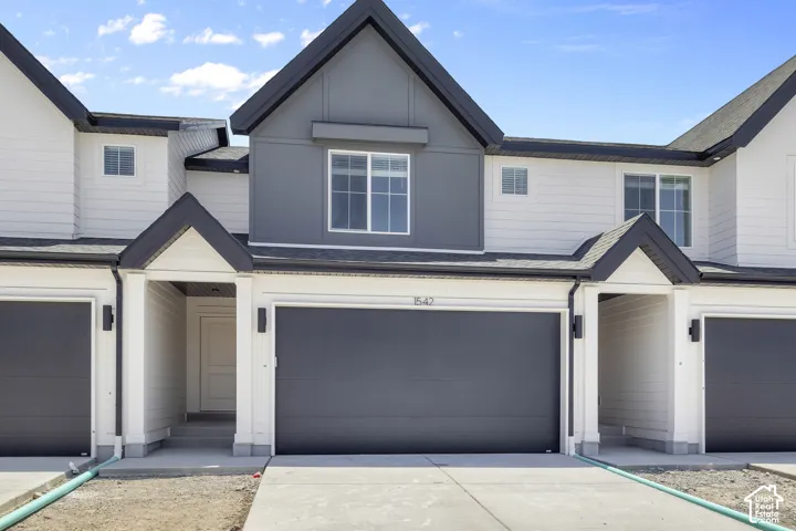 Modern townhouse exterior featuring white siding and dark gray accents