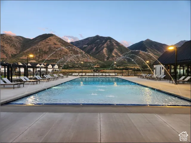 Expansive outdoor swimming pool with water features, surrounded by concrete decking and lounging areas