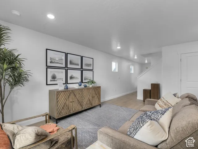 Recessed ceiling lighting, light wood-finish flooring, white walls, and a staircase with white railing