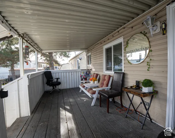 Covered outdoor patio with wood-finish flooring, white railing, and exterior wall siding
