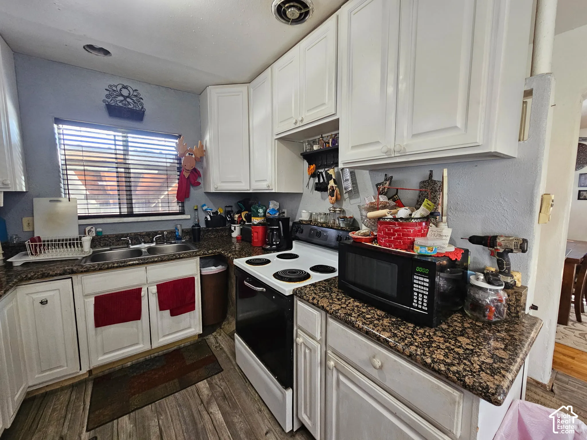 Kitchen featuring white cabinetry, wood-finish flooring, a double basin sink, and a four-burner electric range