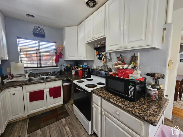 Kitchen featuring white cabinetry, wood-finish flooring, a double basin sink, and a four-burner electric range