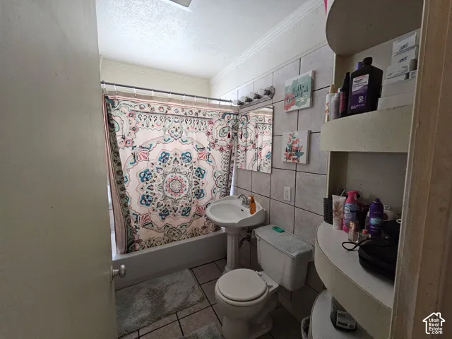 Bathtub with tile surround, pedestal sink, wall-mounted mirror, vanity lighting, and built-in shelving