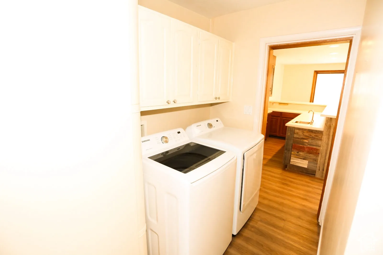 White cabinetry, wood-finish flooring, and a built-in sink in the adjacent space