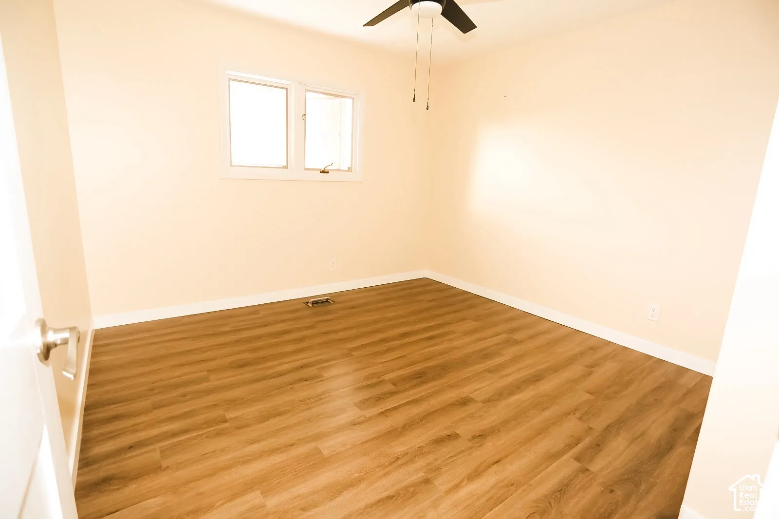 Wood-finish flooring, white trim, and a ceiling fan with integrated lighting