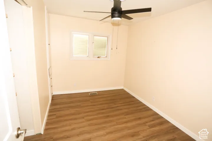 Wood-finish flooring, built-in cabinetry with drawers, multi-pane window, ceiling fan with integrated lighting, and neutral wall tones