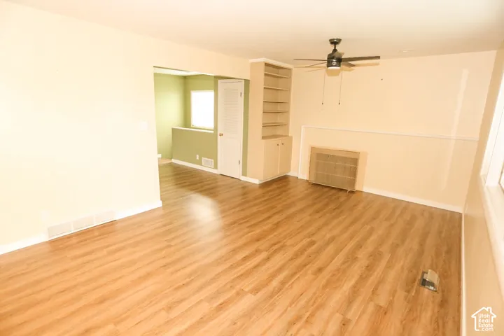 Wood-finish flooring throughout, built-in shelving, ceiling fan light fixture, and white trim molding