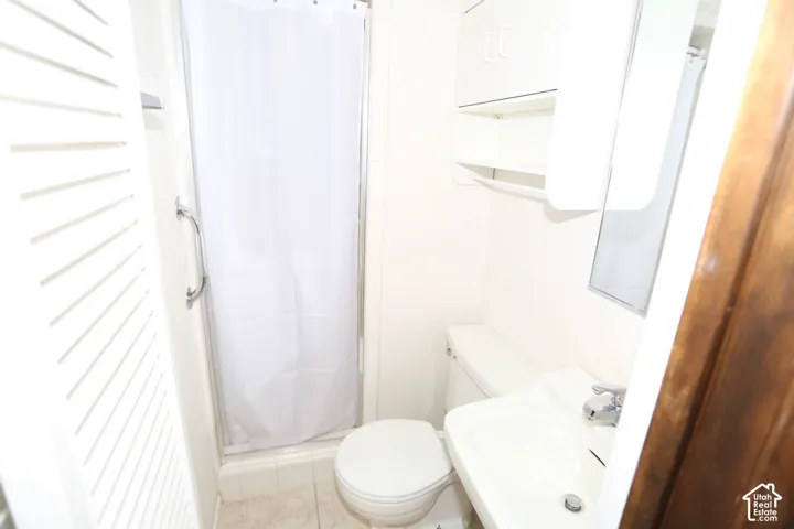 Wall-mounted sink with chrome faucet, built-in storage cabinet with open shelving, and a shower enclosure