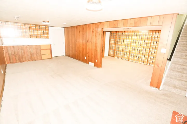 Carpeted flooring, wood paneling, built-in shelving, and a doorway