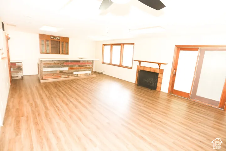 Wood-finish flooring throughout, integrated bar with reclaimed wood paneling, built-in display cabinetry, brick-surround fireplace with wood mantel, and sliding glass door
