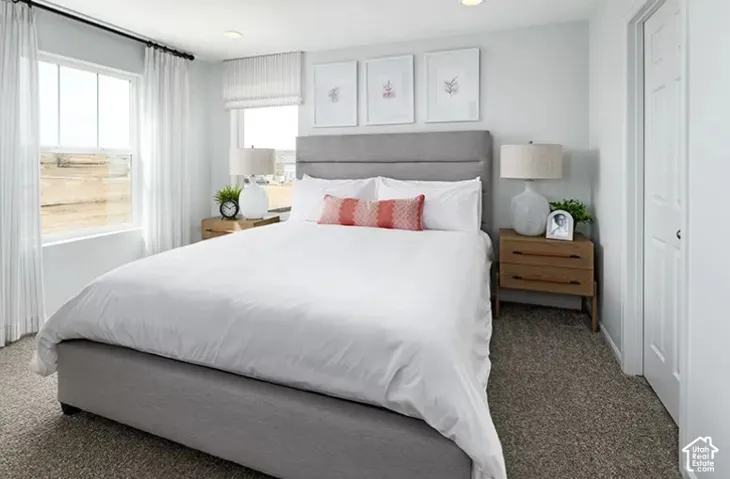 Carpeted room with white walls, two windows featuring white blinds and sheer curtains, and a solid white door