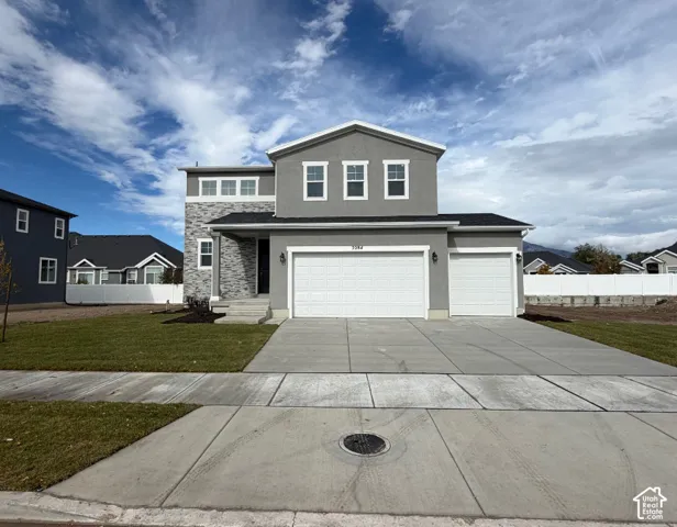 Two-story exterior featuring a gray stucco facade with stone veneer accents, a three-car garage, and a concrete driveway