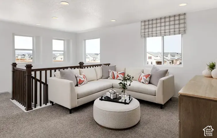 Carpeted common area featuring multiple windows, recessed lighting, and a dark wood-finish railing