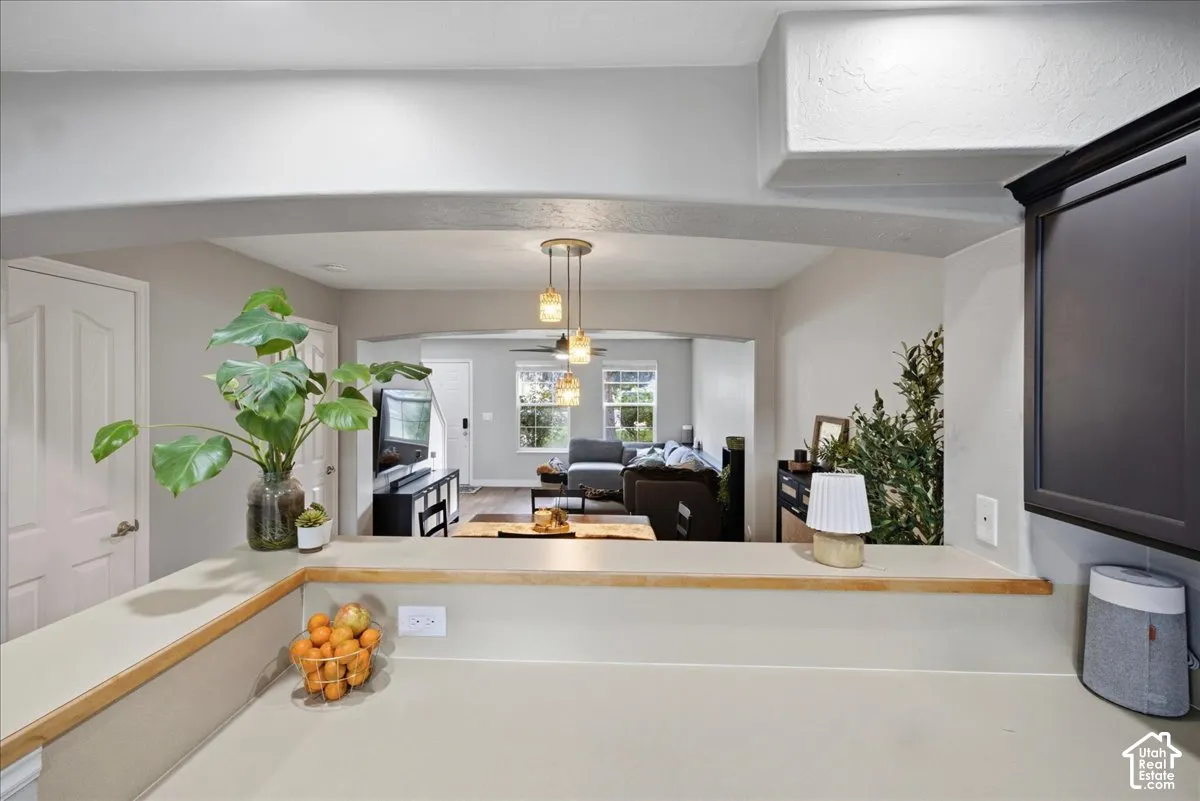 Kitchen pass-through featuring a light-toned countertop, wood trim, and an arched opening to the living area