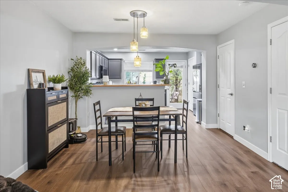 Wood-finish flooring, light gray wall color, arched doorway, recessed lighting, and a multi-pendant light fixture
