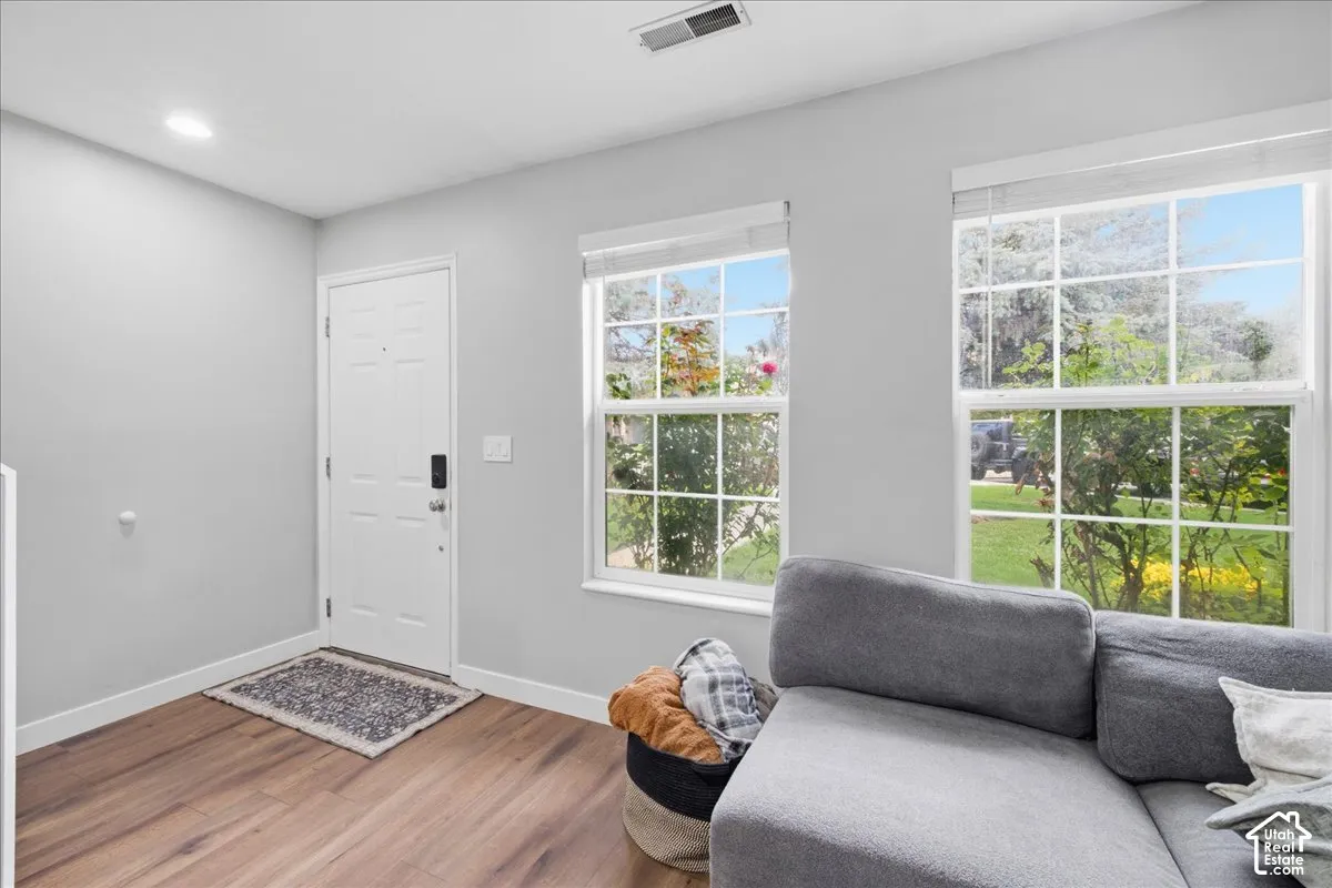 Light gray wall paint, wood-finish flooring, white trim, recessed lighting, and a white entry door with smart lock